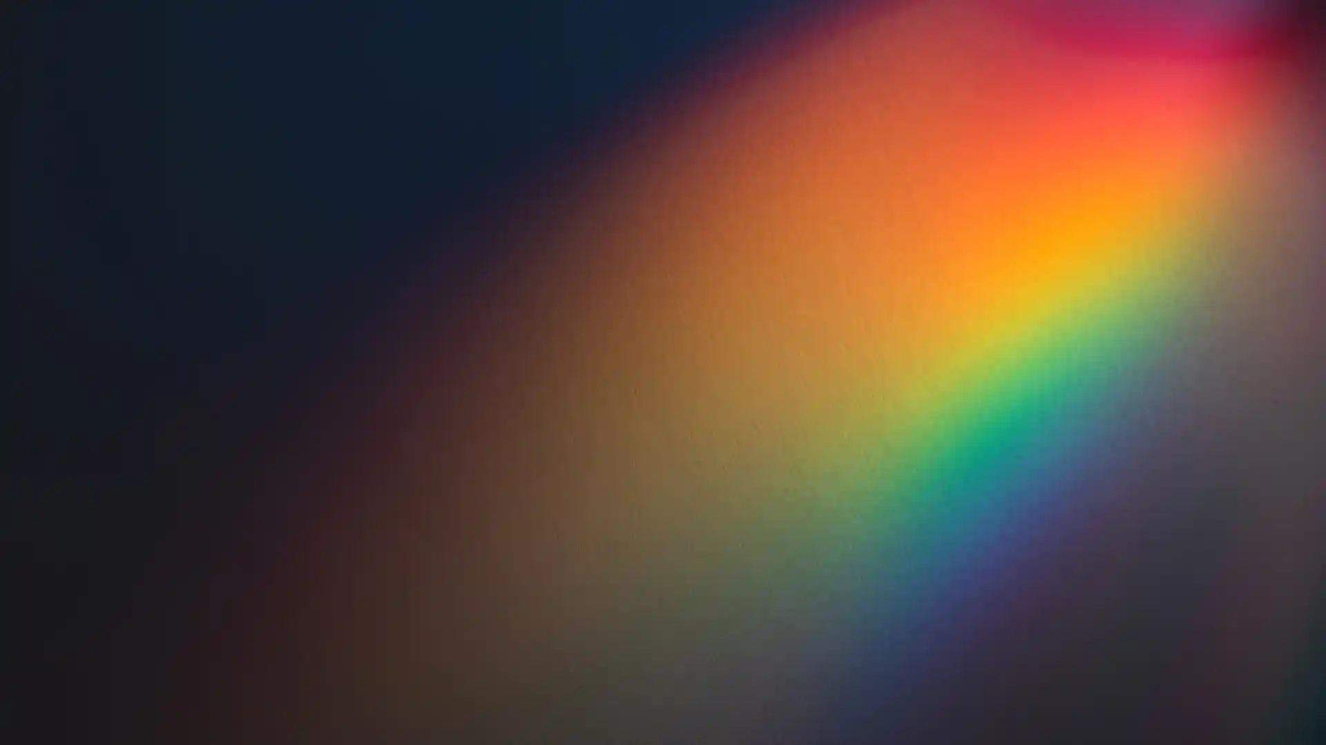 黒い背景に虹色の光が当たっている