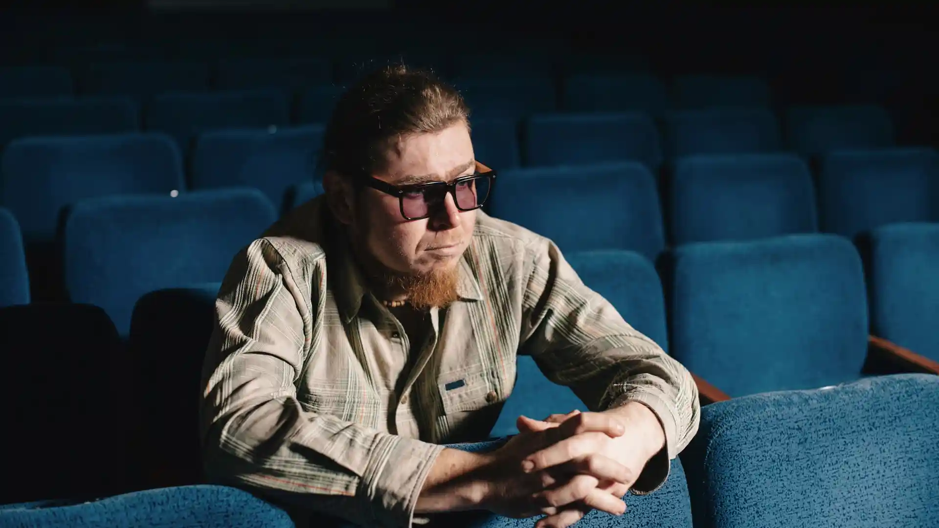 映画コメンテイターの男性が椅子に座って腕を組んでいる