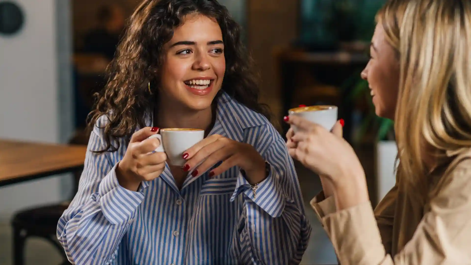 女性二人がコーヒーを飲みながら楽しそうに会話している