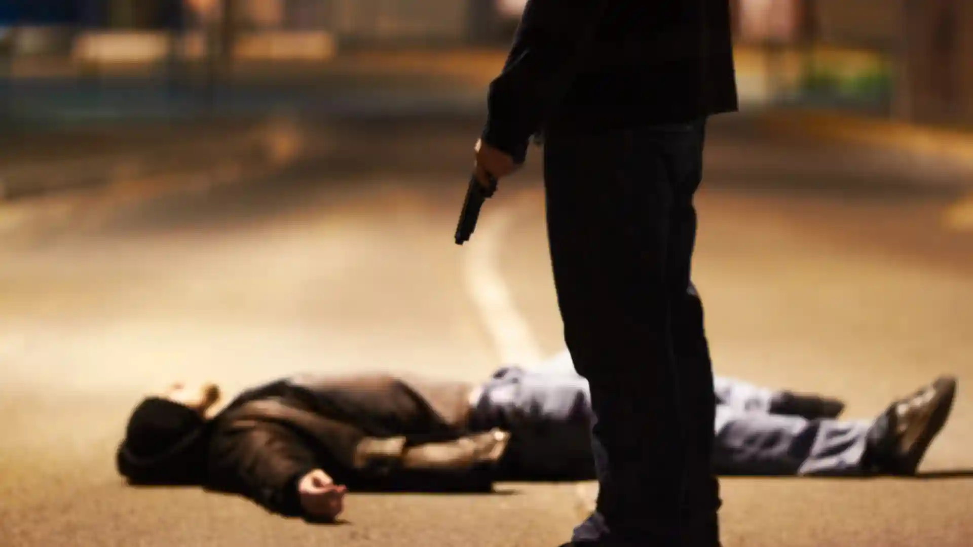 銃を持って立っている男性と銃で撃たれて倒れている男性